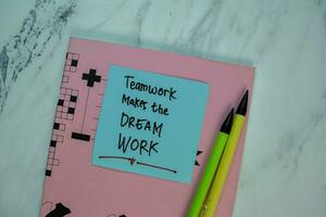 Teamwork Makes The Dream Work write on sticky note isolated on Wooden Table. Motivation concept photo