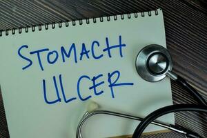 Concept of Stomach Ulcer write on a book isolated on Wooden Table. photo