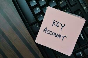 Concept of Key Account write on sticky notes with keyboard computer isolated on Wooden Table. photo