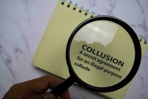 Collusion Meaning Concept write on a book isolated on Office Desk. photo