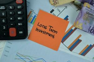 Concept of Long Term Investment write on sticky notes isolated on Wooden Table. photo
