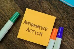 Concept of Affirmative Action write on sticky notes isolated on Wooden Table. photo