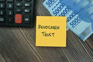 Concept of Revocable Trust write on sticky notes isolated on Wooden Table. photo