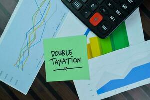 Double Taxation write on sticky notes isolated on Wooden Table. photo