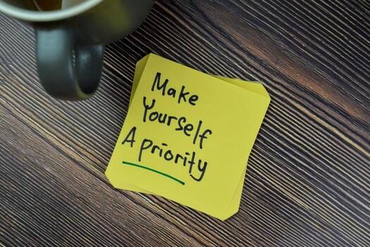 Concept of Make Yourself A Priority Reminder write on sticky notes isolated on Wooden Table. photo