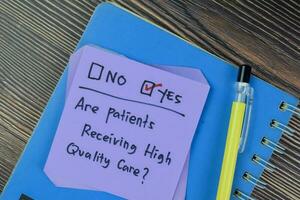 Concept of Are patients Receiving high Quality Care Yes write on sticky notes isolated on Wooden Table. photo