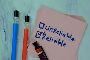 Concept of Unreliable or Reliable write on sticky notes isolated on Wooden Table. photo