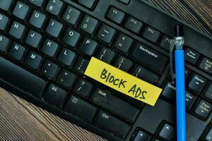 Concept of Block Ads write on sticky notes isolated on Wooden Table. photo