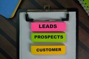 Leads Prospects Customer write on sticky notes isolated on Wooden Table. photo