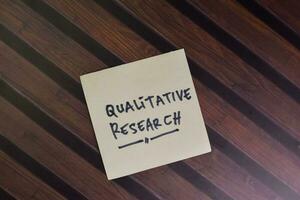 Qualitive Research write on sticky notes isolated on Wooden Table. photo