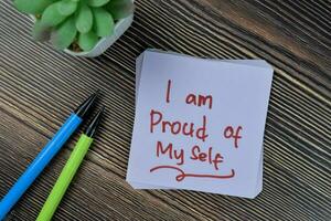 Concept of I am proud of my self write on sticky notes isolated on Wooden Table. photo