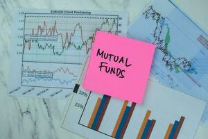 Concept of Mutual Funds write on sticky notes isolated on Wooden Table. photo