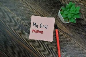 Concept of My First Million write on sticky notes isolated on Wooden Table. photo