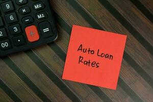 Auto Loan Rates write on sticky notes isolated on Wooden Table. photo
