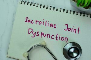 Concept of Sacroiliac Joint Dysfunction write on a book isolated on Wooden Table. photo