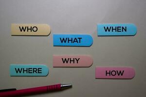 Who, What, When, Where, Why, How write on a sticky note isolated on office desk. photo