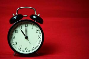Clock ticking to 11 o'clock on the red background photo