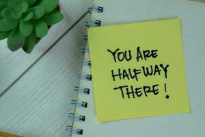 Concept of You Are Halfway There write on a book isolated on Wooden Table. photo