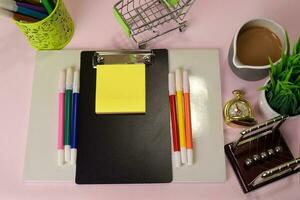 Top view of the notepad and clipboard with a marker drawing on a pink table, preparing to do homework. Drawing Working Desk Concept. photo