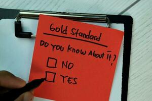 Gold Standard write on sticky notes and supported by additional services isolated on Wooden Table. photo