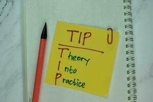 TIP - Theory Into Practice write on sticky note isolated on Wooden Table. photo