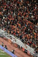 Crowds on Group of fans on the stadium Jakarta International Stadium. Selective focus on banner. Jakarta, Indonesia, August 1, 2022 photo