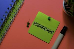 Intrapreneurship write on sticky notes. Isolated on pink table background photo