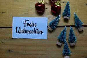 Frohe Weihnachten write on white paper with wooden backgroud. It means Merry Christmas. Frame of Christmas Decoration. photo