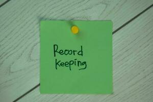 Record Keeping write on sticky notes isolated on Wooden Table. photo