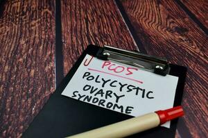 PCOS. Polycystic Ovary Syndrome write on sticky notes. Isolated on wooden table background photo
