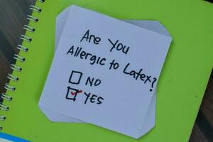 Concept of are you Allergic to Latex Yes write on sticky notes isolated on Wooden Table. photo