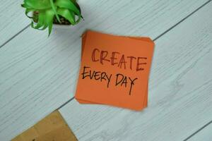 Concept of Create Every day write on sticky notes isolated on Wooden Table. photo