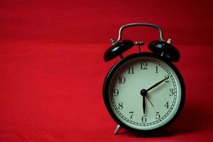 Clock ticking to 6 o'clock on the red background photo