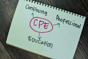 Concept of CPE - Continuing Professional Education write on sticky notes isolated on Wooden Table. photo
