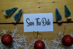 Save The Date write on white paper with wooden backgroud. Frame of Christmas Decoration. photo