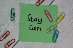 Stay Calm write on sticky notes isolated on Wooden Table. photo