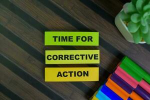 Time For Corrective Action write on sticky notes isolated on Wooden Table. photo