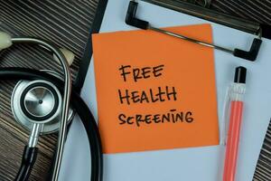 Concept of Free Health Screening write on sticky notes isolated on Wooden Table. photo
