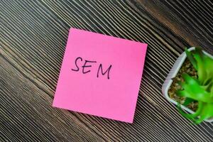 Concept of SEM write on sticky notes isolated on Wooden Table. photo