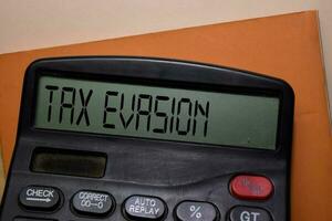 impuesto evasión escribir en el calculadora en oficina escritorio. foto