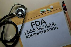 FDA - Food and Drug Administration text on document above brown envelope and stethoscope. Healthcare or medical concept photo