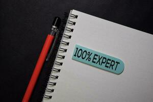 100 percent Expert write on sticky note isolated on black table. photo