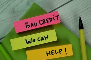 Bad Credit We Can Help write on sticky notes isolated on Wooden Table. photo