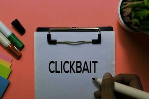 Clickbait write on sticky notes. Isolated on pink table background photo