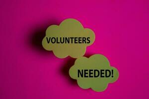 Volunteers Needed write on a sticky note isolated on Office Desk. photo