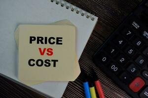 Price Vs Cost write on sticky notes isolated on Wooden Table. photo