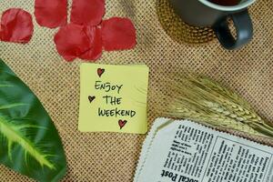 Enjoy The Weekend write on sticky notes isolated on Wooden Table. photo