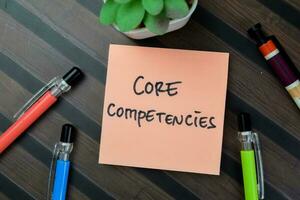 Concept of Core Competencies write on sticky notes isolated on Wooden Table. photo