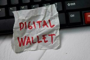 Digital Wallet write on crunched paper isolated on wooden table. photo