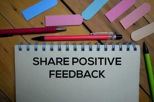 Share Positive Feedback write on a book isolated on wooden background. photo